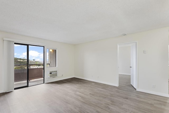 unfurnished room featuring a textured ceiling, baseboards, and wood finished floors