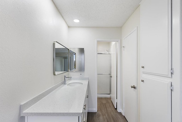 bathroom with vanity, wood finished floors, a stall shower, and a textured ceiling