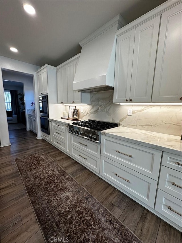 kitchen with dark wood finished floors, custom exhaust hood, white cabinets, gas cooktop, and dobule oven black