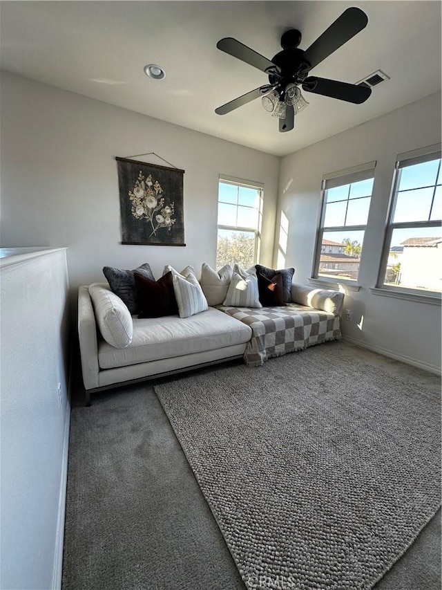 carpeted living room featuring visible vents, baseboards, and ceiling fan