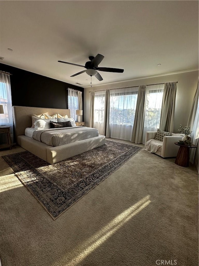 carpeted bedroom featuring multiple windows and ceiling fan