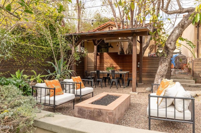 view of patio featuring outdoor dining space, an outdoor living space with a fire pit, and fence