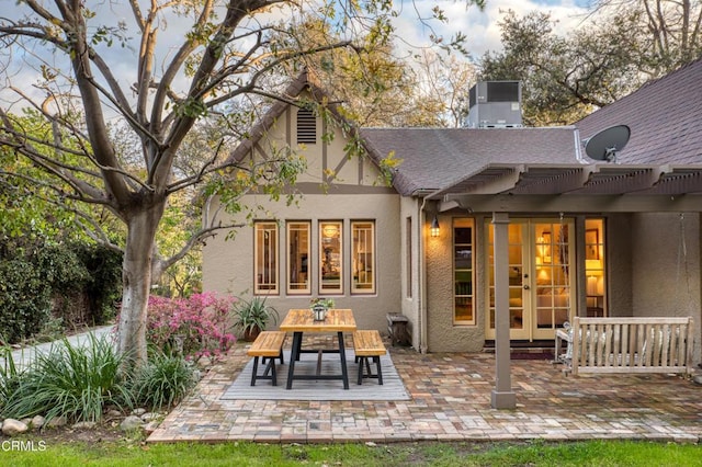 back of house featuring stucco siding, outdoor dining space, cooling unit, a shingled roof, and a patio area