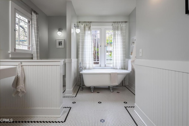 bathroom featuring a freestanding bath, wainscoting, and tile patterned flooring