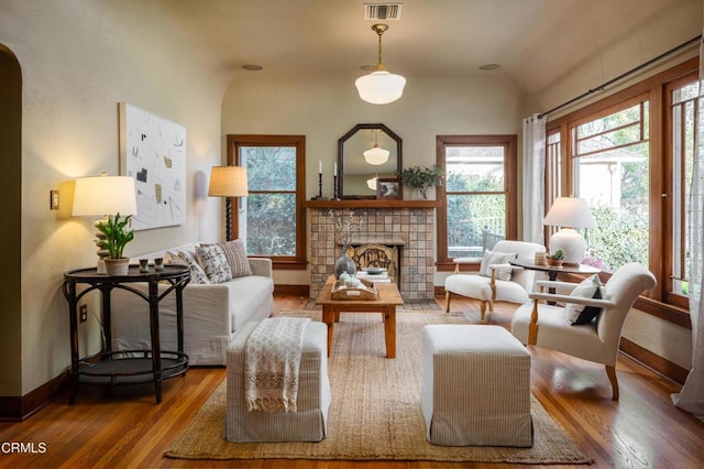 living area with visible vents, a tile fireplace, baseboards, and wood finished floors