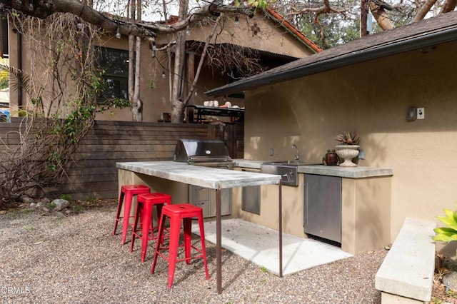 view of patio / terrace featuring area for grilling, a sink, fence, outdoor wet bar, and exterior kitchen