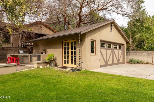 view of front of house featuring a front lawn, fence, stucco siding, a garage, and an outdoor kitchen