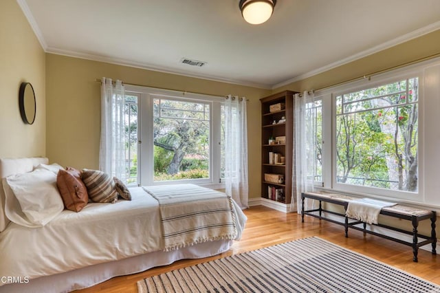 bedroom featuring visible vents, light wood-style flooring, and ornamental molding