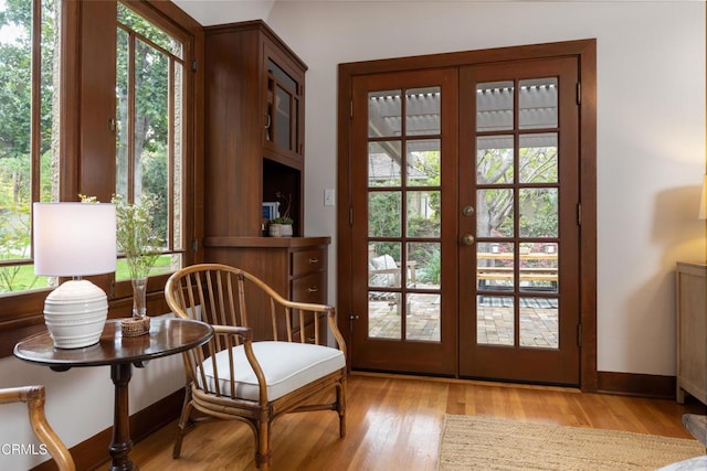 sitting room featuring french doors, light wood-style floors, and a healthy amount of sunlight