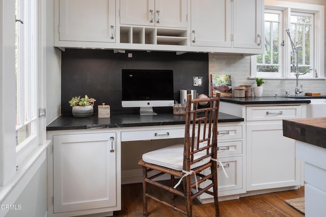 kitchen with decorative backsplash, dark countertops, white cabinetry, and a sink