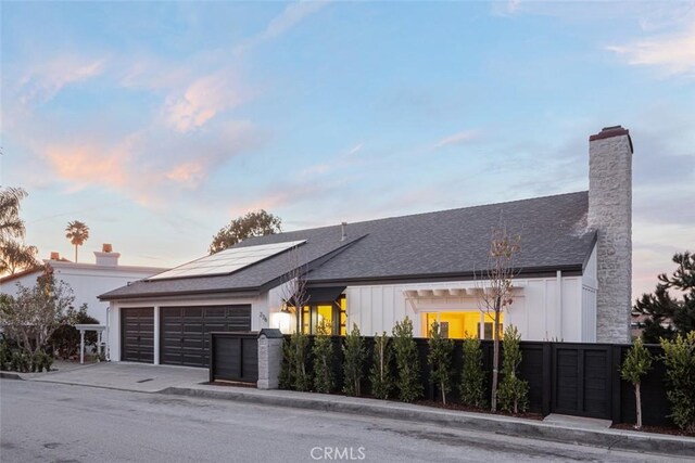 236 Avenida Montalvo, San Clemente, CA 92672 - view of front of house featuring a garage, board and batten siding, solar panels, driveway, and roof with shingles