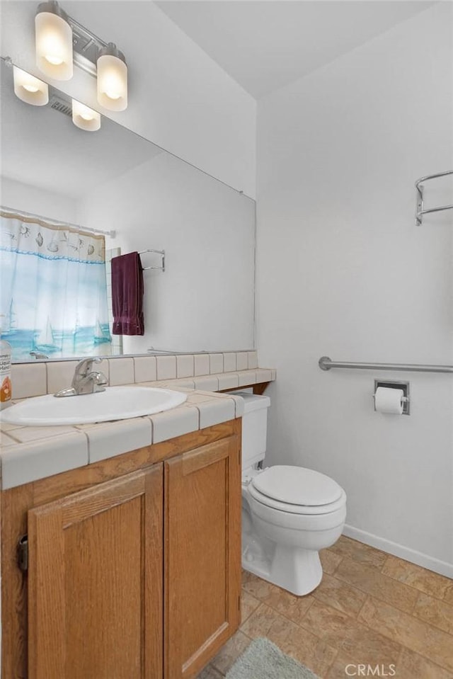 full bathroom with baseboards, toilet, and vanity