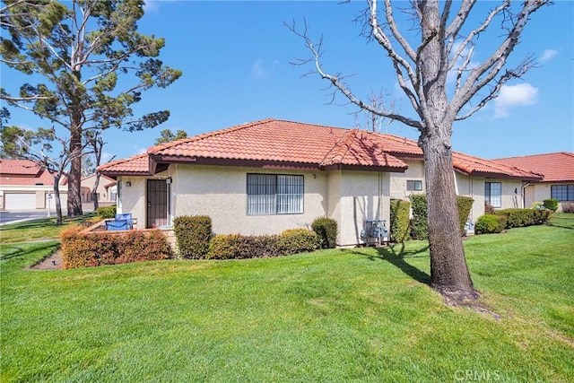 view of front facade featuring a front lawn, a tiled roof, and stucco siding