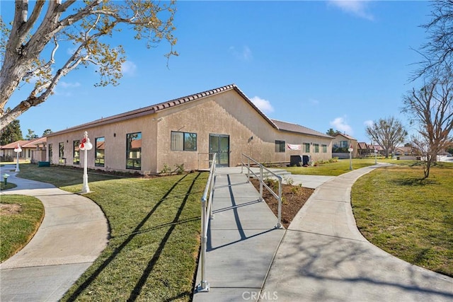 exterior space featuring stucco siding and a front lawn