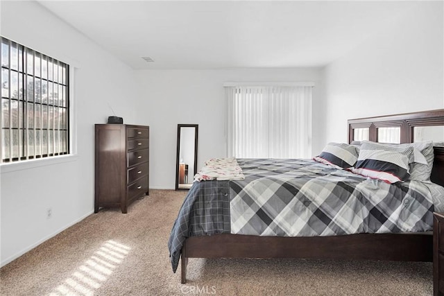 bedroom featuring visible vents, light colored carpet, and baseboards