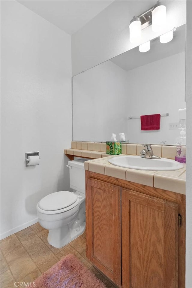 bathroom featuring baseboards, toilet, and vanity