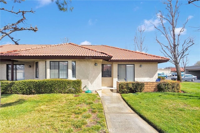 view of front of house with stucco siding, a tiled roof, and a front yard