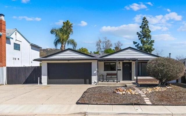 ranch-style home featuring a porch, concrete driveway, a garage, and fence