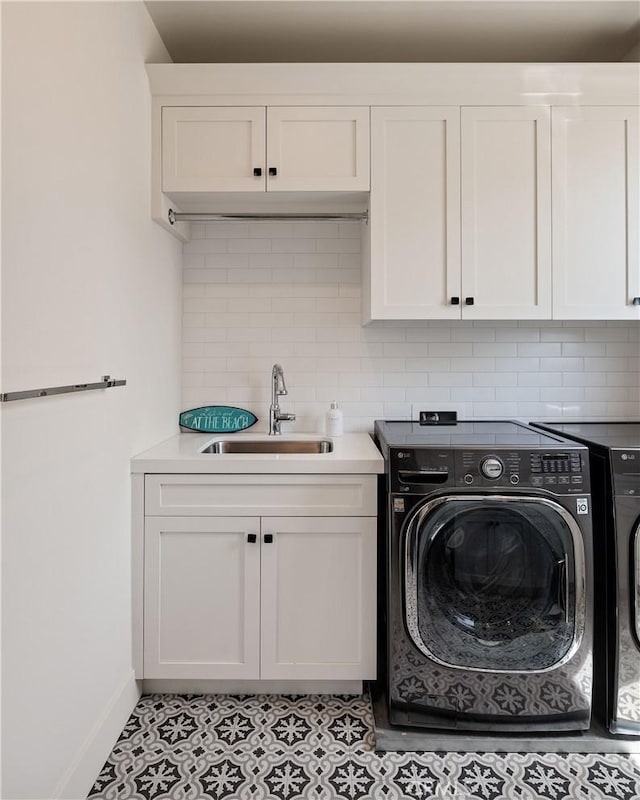 laundry area featuring light tile patterned floors, baseboards, washing machine and clothes dryer, cabinet space, and a sink