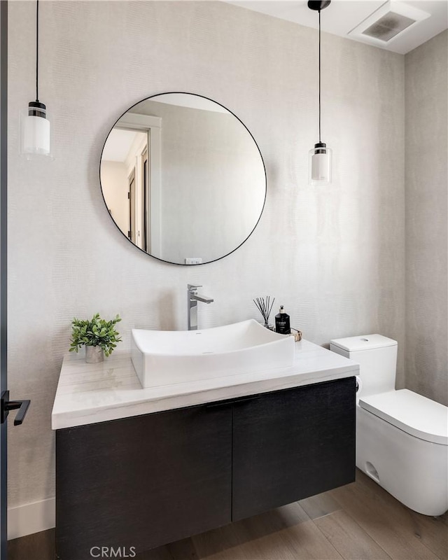 half bath featuring visible vents, toilet, wood finished floors, and vanity