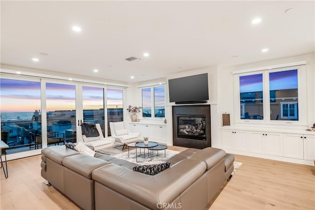 living room with a glass covered fireplace, recessed lighting, and light wood-style floors