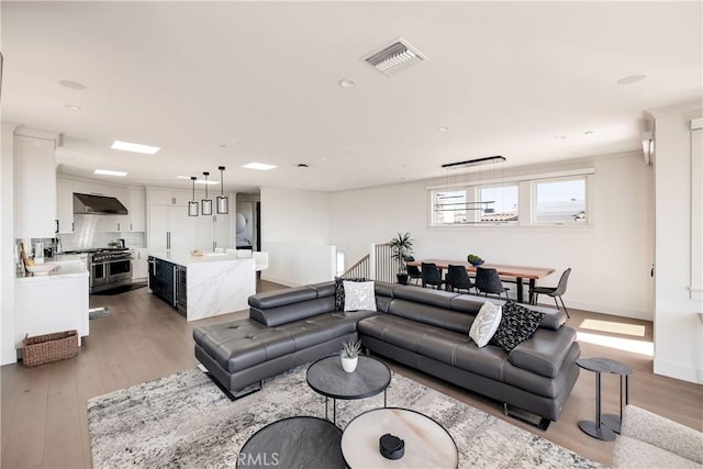 living room with recessed lighting, visible vents, baseboards, and light wood-style flooring