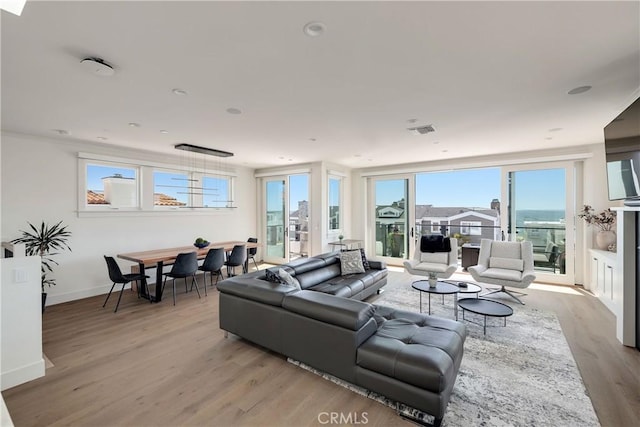 living area with visible vents, baseboards, and light wood-style flooring