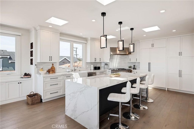 kitchen featuring a sink, a kitchen island, a skylight, and white cabinets