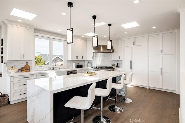 kitchen featuring a sink, a kitchen bar, a kitchen island, and white cabinets