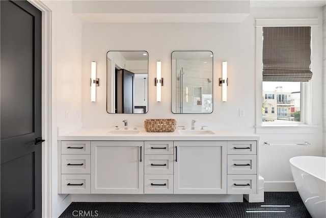 bathroom with a freestanding bath, double vanity, a stall shower, and a sink