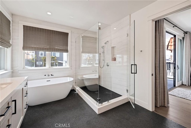 full bath with a stall shower, wood finished floors, recessed lighting, a soaking tub, and vanity