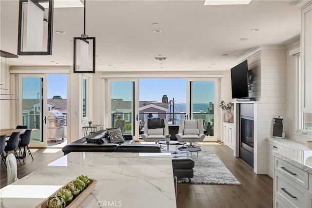 living room featuring wood finished floors, visible vents, recessed lighting, a glass covered fireplace, and crown molding