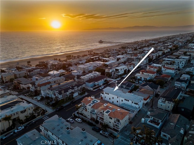 aerial view at dusk with a view of the beach and a water view