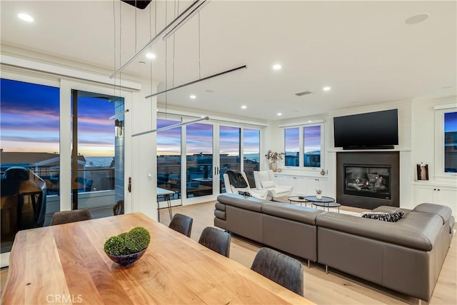 living area featuring light wood finished floors, visible vents, recessed lighting, and a glass covered fireplace