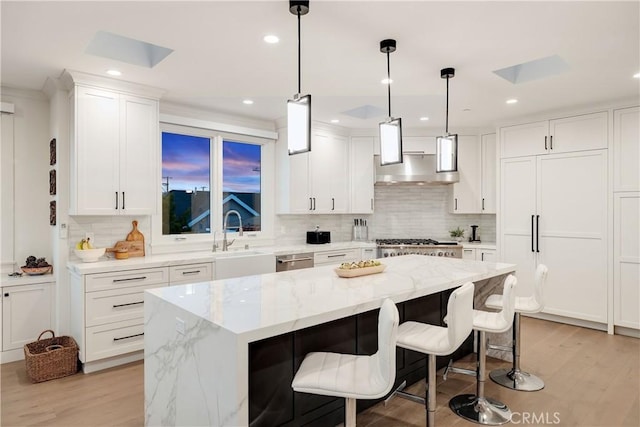 kitchen with a kitchen island, a sink, under cabinet range hood, white cabinetry, and tasteful backsplash