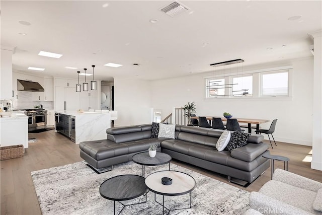 living room featuring light wood-style floors, visible vents, and baseboards