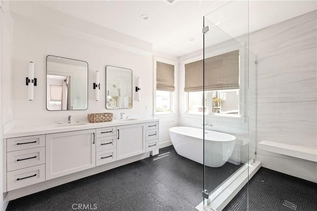 bathroom with double vanity, a freestanding tub, a shower stall, and a sink