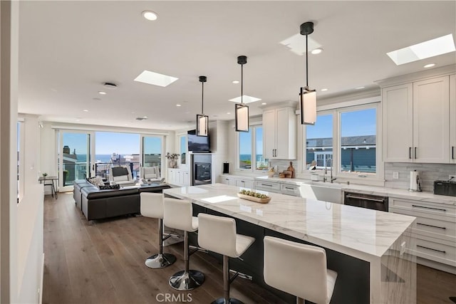 kitchen featuring a breakfast bar, decorative backsplash, a skylight, and a sink