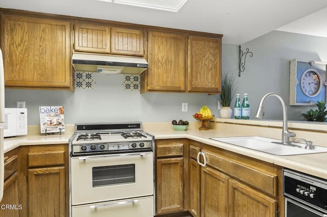 kitchen with white appliances, brown cabinetry, a sink, light countertops, and under cabinet range hood