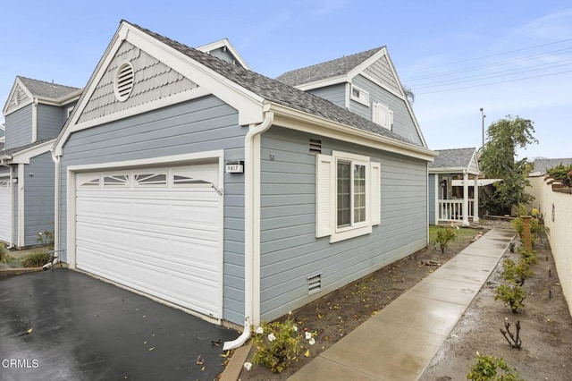 view of property exterior with an attached garage, driveway, and fence