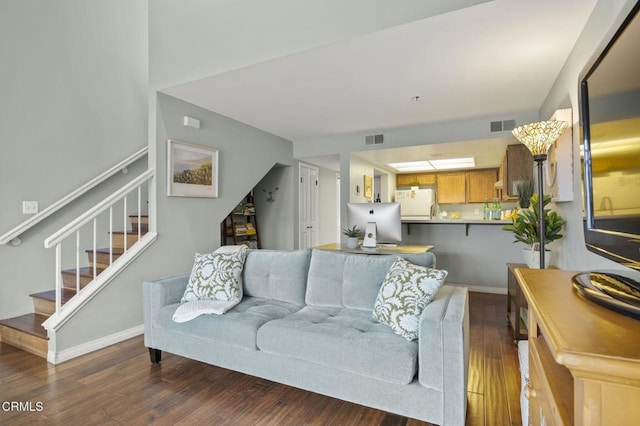 living room with visible vents, stairs, baseboards, and wood finished floors