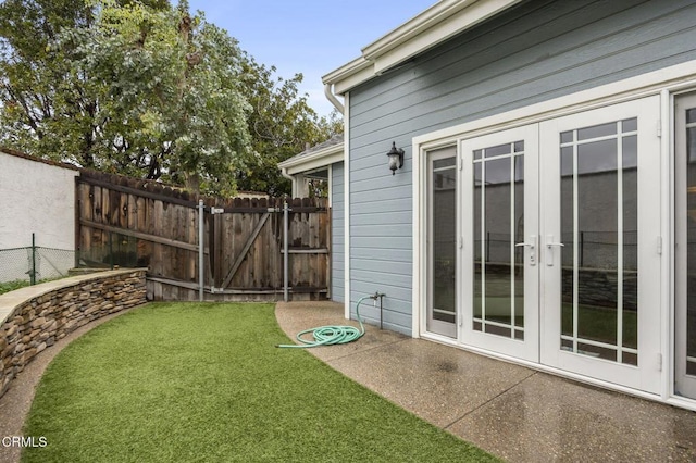 view of yard featuring a gate, fence, and french doors