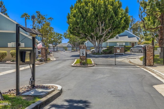 view of road with curbs, a residential view, a gated entry, and a gate