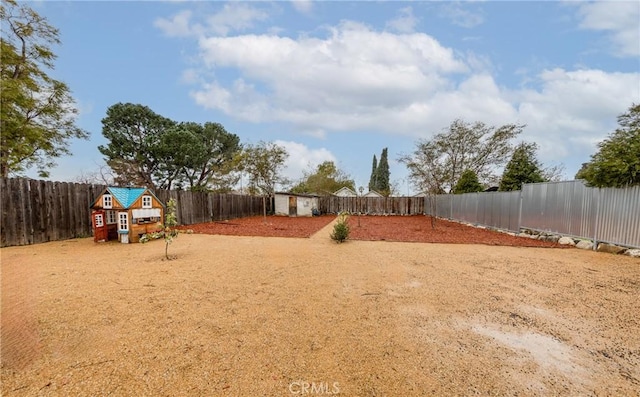 view of yard featuring a storage unit, an outbuilding, and a fenced backyard