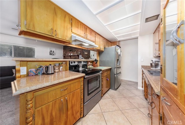 kitchen with light tile patterned floors, brown cabinets, under cabinet range hood, appliances with stainless steel finishes, and tasteful backsplash