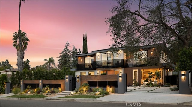 contemporary house featuring a fenced front yard, stucco siding, and a balcony