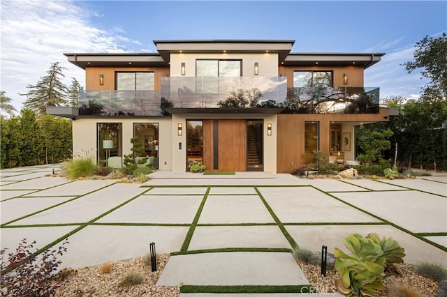 rear view of property featuring a balcony and stucco siding