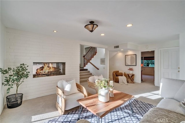 carpeted living room featuring stairs, a brick fireplace, recessed lighting, and visible vents