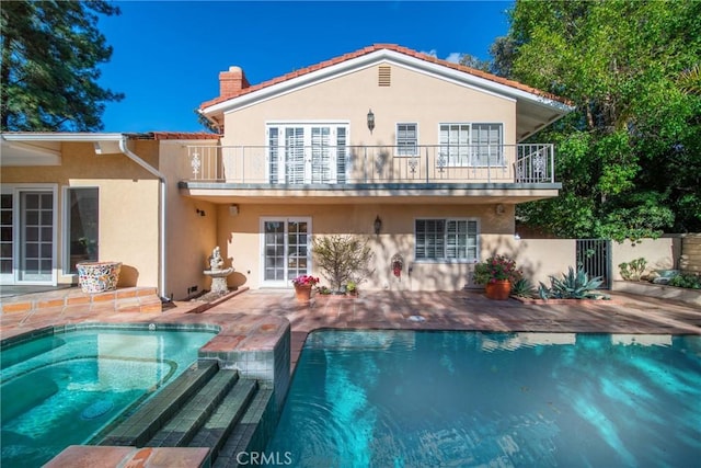 rear view of property featuring stucco siding, a patio, a chimney, and a balcony