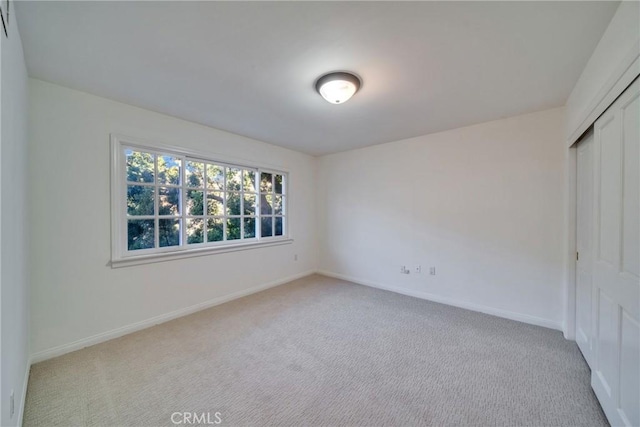 unfurnished bedroom featuring carpet flooring, baseboards, and a closet